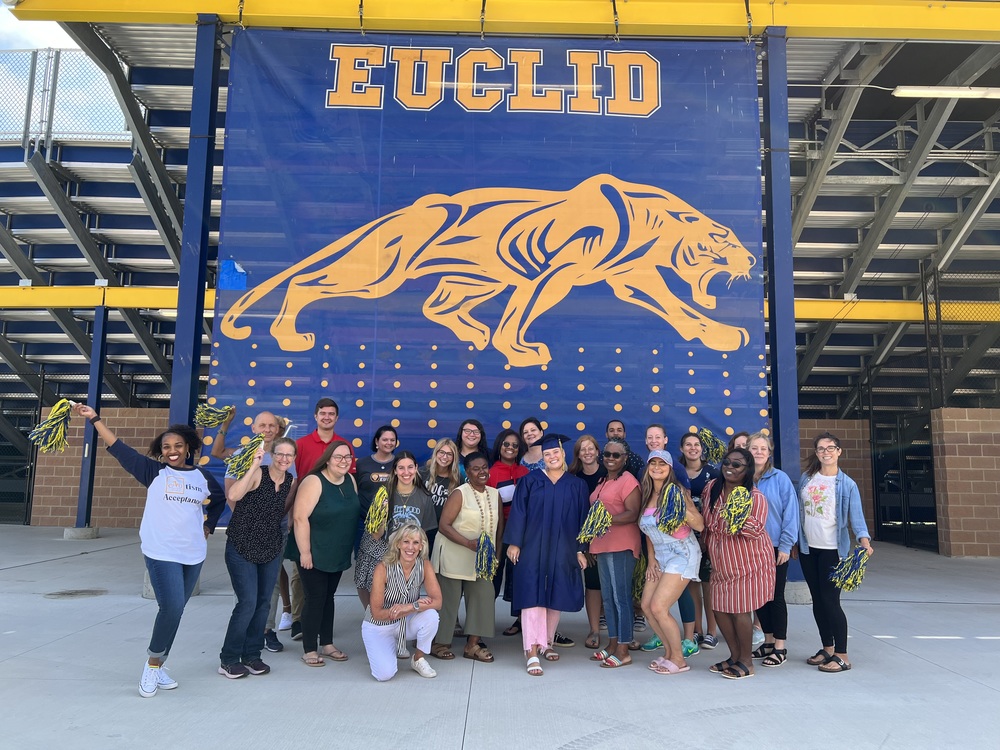 Teachers posing in front of Euclid banner
